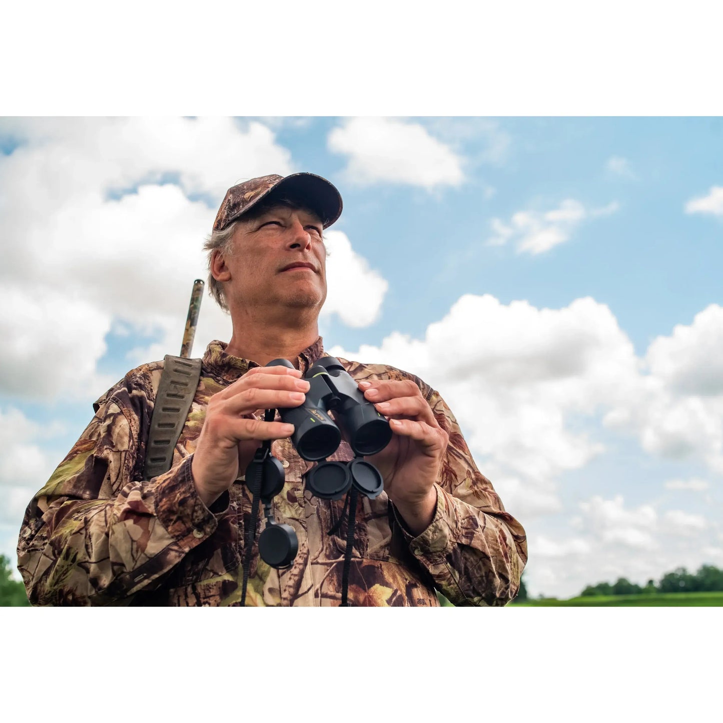 Man hunting in camo holding the Alpen Apex 10x42 Binoculars