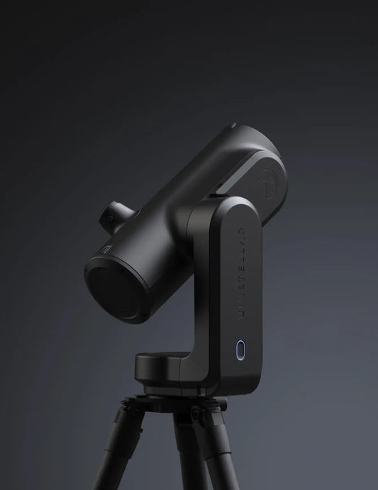 Black Unistellar telescope on a tripod against a dark background