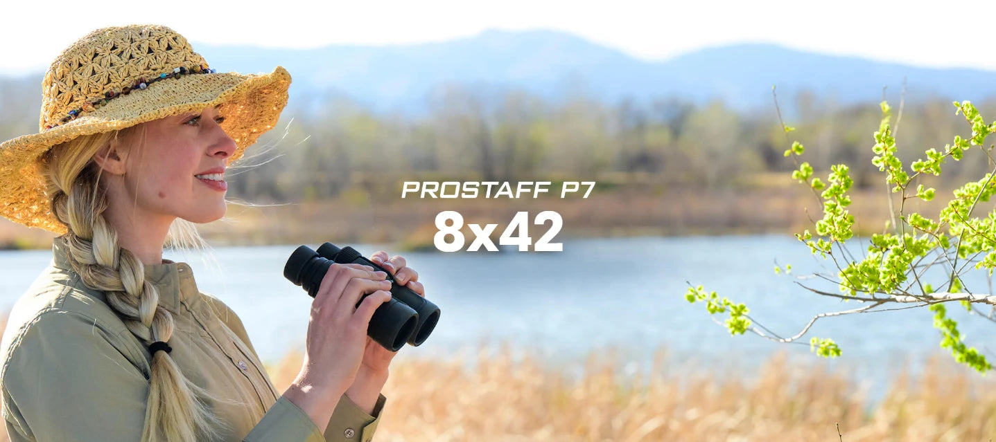 Woman holding binoculars with Prostaff P7 8x42 label by a lake