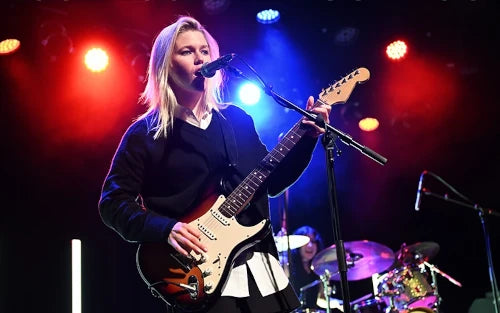 Person playing guitar on stage with colorful lights