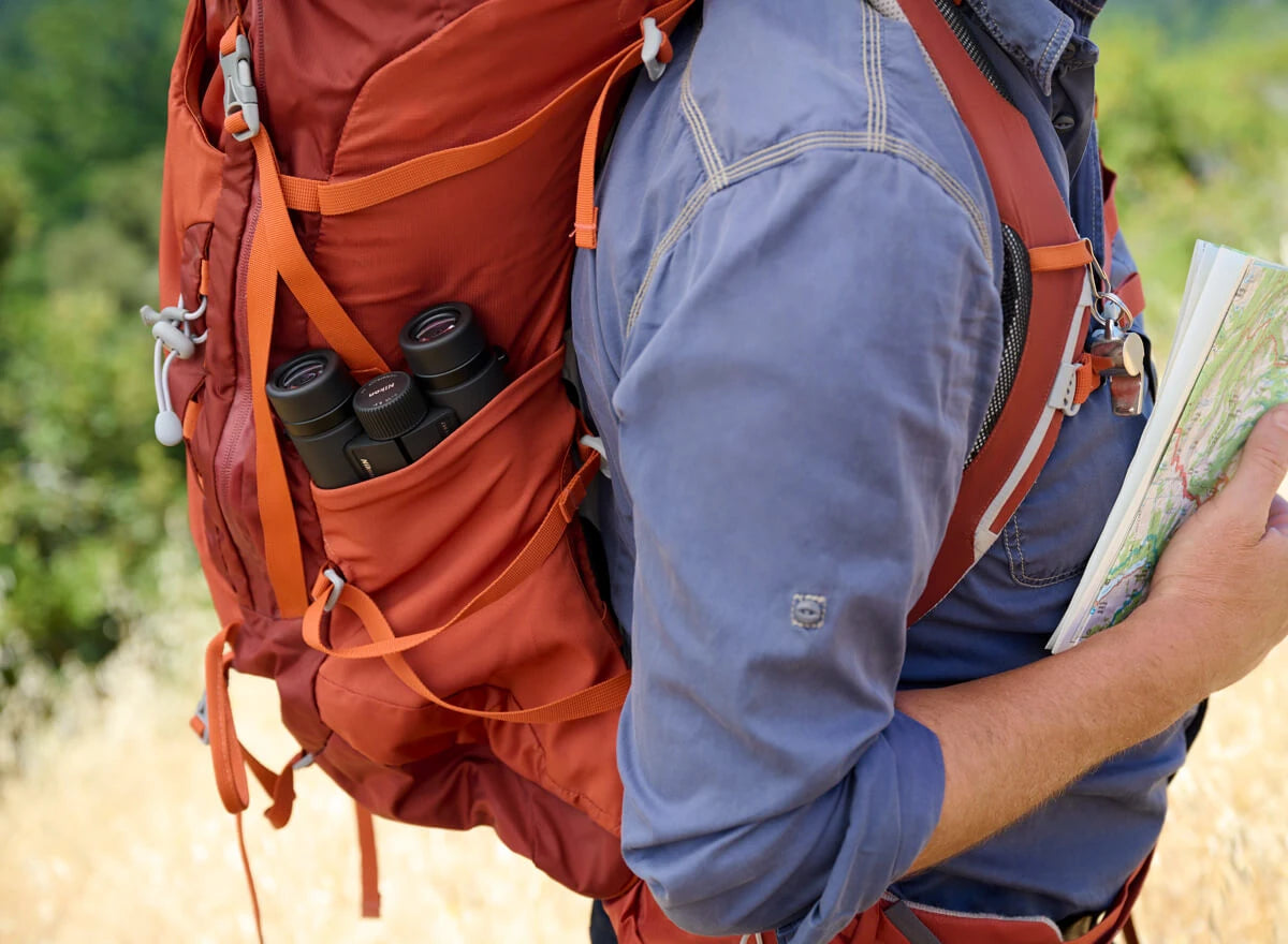 The Nikon binoculars placed in a side pocket of a hikers backpack.