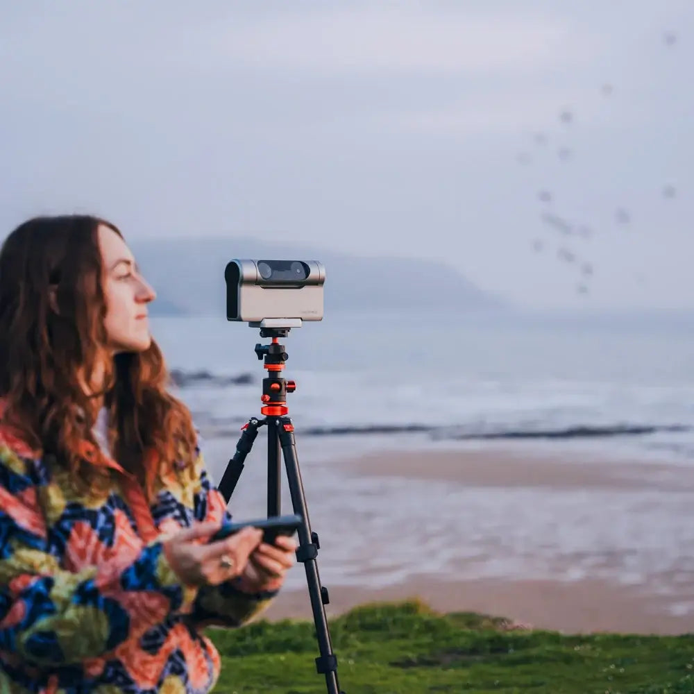 Person with a DWARF Telescope on a tripod by the beach