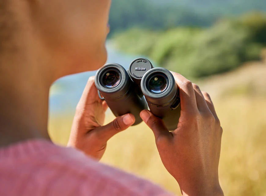 Person holding binoculars just off the side of their neck.