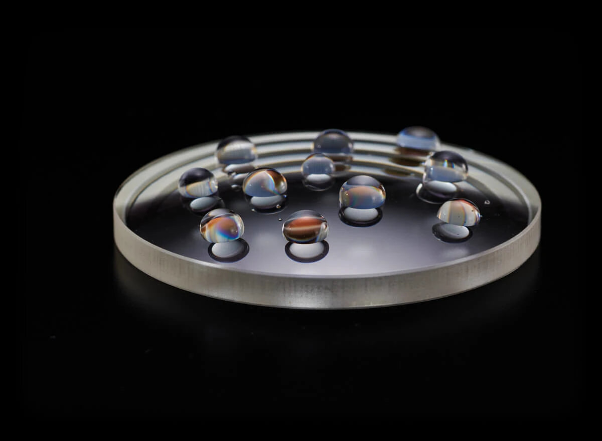 Water droplets balancing on a glass lens.