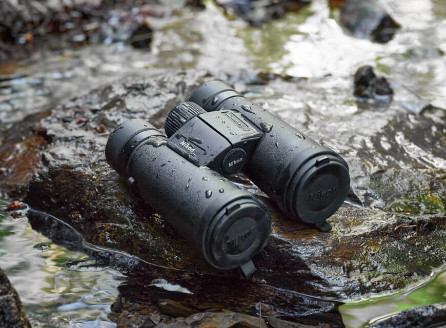 Binoculars elevated on a wet rock surrounded by a stream of water.